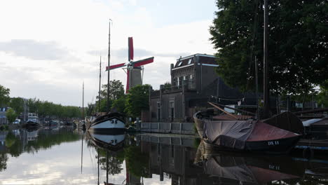 Boats-In-The-Canal-With-Molen-de-Roode-Leeuw-In-The-Backgound-In-Turfsingel,-Gouda,-Netherlands