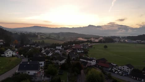 Aufsteigende-Drohnenaufnahme,-Die-Die-Schweizer-Nachbarschaft-Während-Des-Goldenen-Sonnenuntergangs-In-Eschenbach,-Schweiz-Zeigt---Alpen-Im-Hintergrund