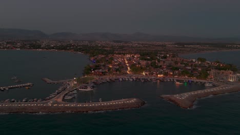 Aerial-view-circling-illuminated-Side-old-town-marina-and-coastline-neighbourhood-homes-at-sundown