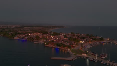 Aerial-view-across-illuminated-Side-old-town-marina-and-Turkish-coastal-real-estate-neighbourhood-after-sunset