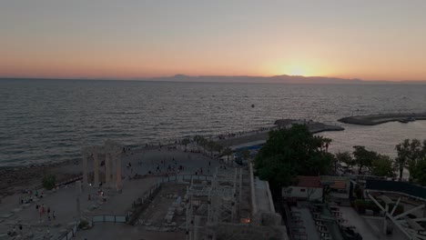 Side-harbour-waterfront-aerial-view-sunset-sky-over-old-town-and-Apollon-temple-Greek-classical-ruins
