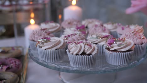Leckere-Cupcakes-Auf-Dekoriertem-Tisch,-Rückwärtsbewegung-Des-Dollys,-Kerzen-Im-Hintergrund