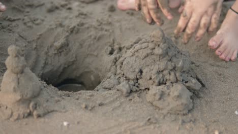 Close-up-shot-of-a-child-who-wants-to-build-a-sandcastle-with-the-sand-on-the-beach-during-summer-vacation-and-is-having-fun-on-the-trip-together-with-her-parents-in-slow-motion