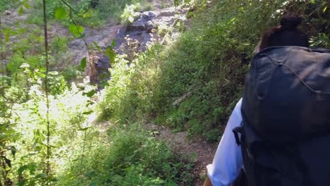 Female-Hispanic-backpacker-hikes-down-narrow-forest-path-in-Honduras