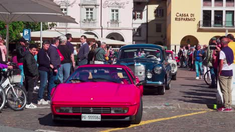 Oldtimer-Verlassen-Ihren-Treffpunkt-Am-Waltherplatz-In-Bozen,-Südtirol,-Während-Auf-Beiden-Seiten-Zuschauer-Stehen-Und-Den-Autos-Beim-Losfahren-Zusehen