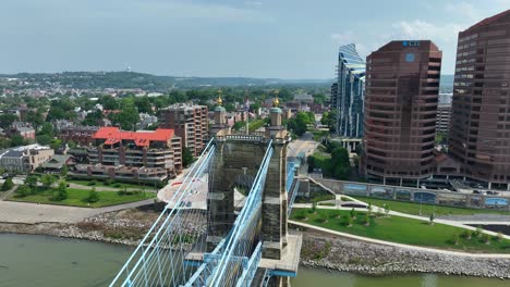 Vista-Aérea-De-Covington,-Kentucky:-Puente-Roebling-Que-Cruza-El-Río-Ohio,-Flanqueado-Por-Modernos-Rascacielos,-CTI