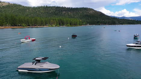 Drone-shot-over-moored-boats-rising-toward-the-shore-of-Lake-Tahoe,-in-sunny-USA