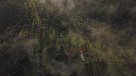 Dramatic-pan-and-tilt-drone-shot-over-the-clouds-looking-down-on-the-dramatic-hillside-and-trees