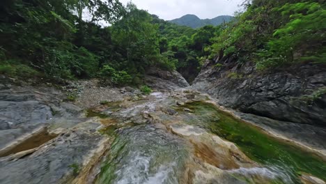 Fpv-drone-flight-over-rocky-river-bani-surrounded-by-vegetated-nature-on-Dominican-Republic