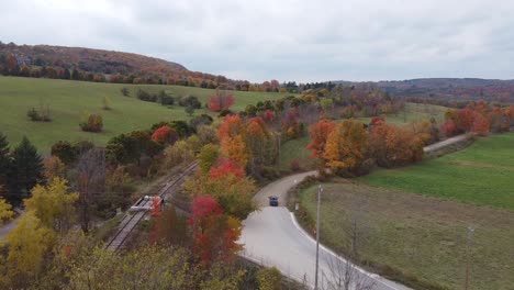 Aerial-Shot-Of-A-Car-Driving-Through-Fall-Colour-Landscape,-Caledon