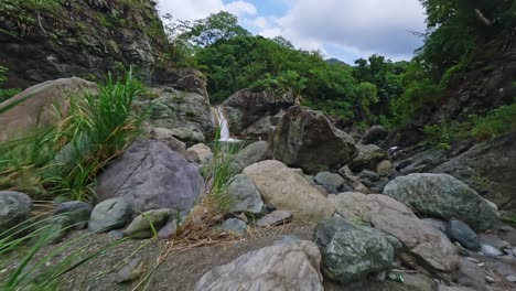 Aerial-drone-flight-over-giant-rock-approaching-LAS-YAYITAS-Waterfall-in-BANI---People-swimming-and-resting-in-tropical-pond