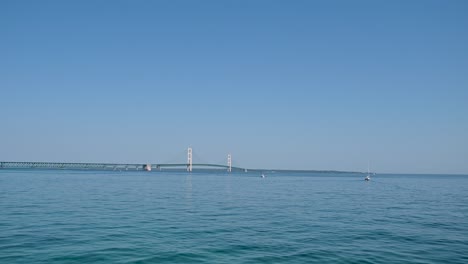 Boat-view-of-Mackinac-Bridge-and-sailboat,-Michigan