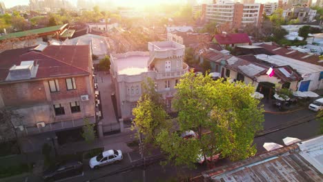 Dolly-out-aerial-view-of-the-sun-rays-at-sunset-in-the-Santa-Isabel-neighborhood-with-the-Castillito-Sermini,-residential-neighborhood-of-Providencia,-Chile