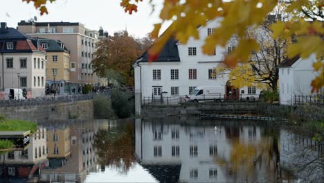 Stadtfluss-Mit-Herbstblättern-Und-Alten-Gebäuden-In-Einer-Malerischen-Städtischen-Umgebung