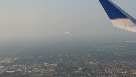 Looking-Out-Plane-Window-To-See-Another-Plane-Flying-Through-Fog