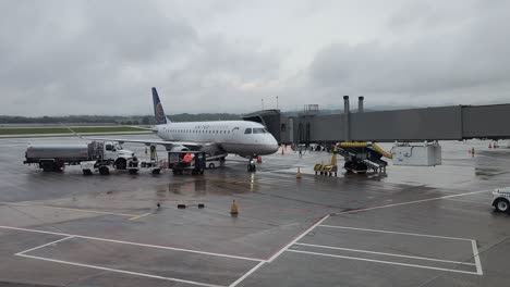 Airport-Ground-Staff-Unloading-Luggage-From-United-Plane-Whilst-Connected-To-Jet-Bridge-On-Overcast-Day