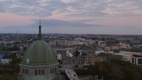 Dynamic-aerial-shot-of-Galway-City-during-sunset,-flying-over-the-Cathedral