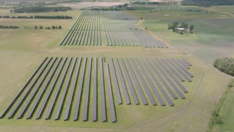 Rows-of-solar-panels-on-a-rural-field-in-Sjobo,-Sweden,-aerial-forward