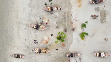 Blick-Von-Oben-Auf-Fischer,-Die-Fischernetze-In-Der-Nähe-Von-Holzbooten-Am-Ufer-Von-Kuakata,-Bangladesch,-Reparieren