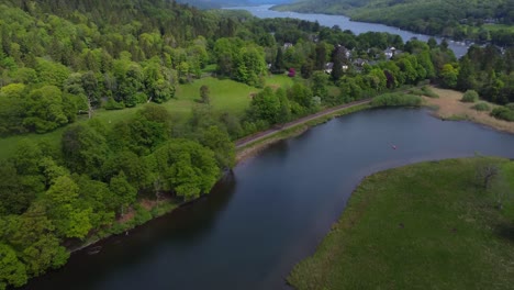 Aerial-drone-video-4K-of-beautiful-green-summer-landscape-of-a-lake,-forest-and-mountains-in-the-background---taken-at-Windermere,-Lake-District