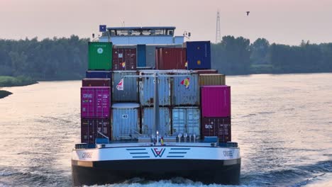 Cargo-ship-with-containers-and-colored-flags-Crigee-Noord-sailing-along-the-banks-of-the-Hoaldn-river