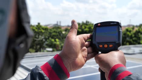 Asian-Technician-use-Thermo-Device-to-Check-the-Heat-on-Roof-Top-Solar-Panel,-Close-Up