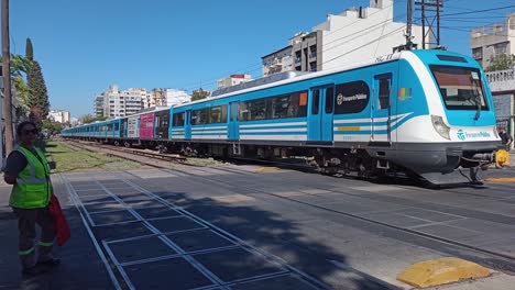 Passenger-train-circulating-at-level-crossing-with-traffic-control-person-in-Buenos-Aires,-Argentina