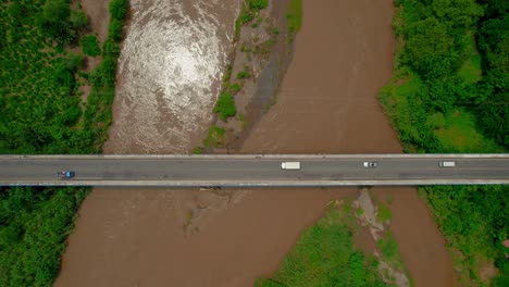 Aerial-over-a-busy-highway-and-muddy-waters-of-River-Tarcoles,-Costa-Rica