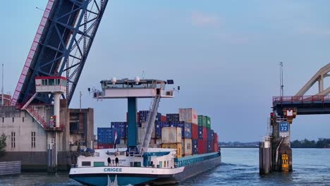 Cargo-ship-with-containers-sails-over-a-raised-bridge-on-a-river