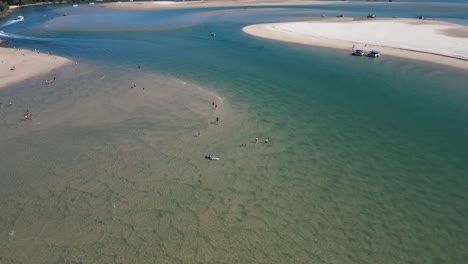 Aerial-orbits-kayaker,-beach-goers-at-sandy-Noosa-Heads,-Queensland