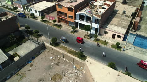 Drone-shot-around-men-skating-through-the-streets-of-sunny-Huacho-city,-Peru