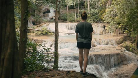 Attracitve-Young-Woman-Hiking-Next-to-Waterfall-in-Erawan-National-Park,-Thailand