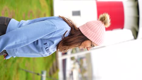 Vertical-shot-of-smiling-woman-wearing-hoodie-with-Faroe-Islands-sign,-Skansin