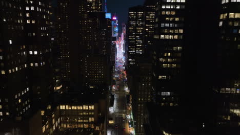 Disparo-De-Un-Dron-Inclinándose-Sobre-La-7ma-Avenida,-A-Través-Del-Iluminado-Centro-De-La-Ciudad-Hasta-Times-Square,-Nueva-York