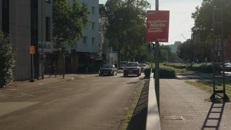 Frau-Geht-über-Die-Straße,-Während-Autos-Bei-Sonnenuntergang-Die-Straße-Entlang-Fahren-Und-In-Der-Stadt-Pendeln