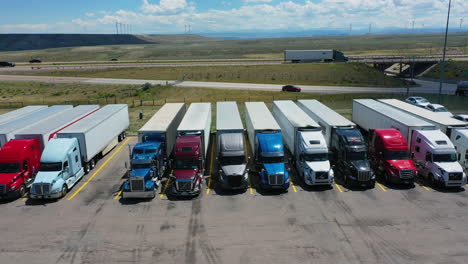 Seguimiento-Aéreo-De-Semirremolques-Estacionados-En-Una-Parada-De-Camiones,-Día-Soleado-En-EE.UU.