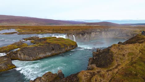 Luftaufnahme-Eines-Majestätischen-Wasserfalls-Mit-Türkisfarbenem-Wasser,-Malerischer-Landschaft-Und-Touristenziel-In-Island