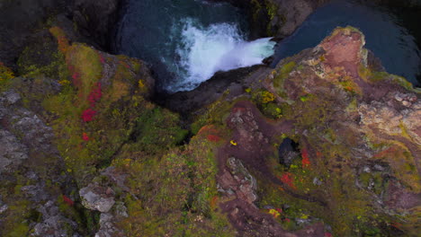 Man-walking-on-top-of-waterfall-canyon-in-autumnal-Iceland