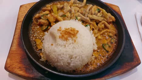 Overhead-view-of-sizzling-bicol-express-and-rice-on-a-hot-plate,-a-popular-authentic-traditional-dish-from-the-Philippines