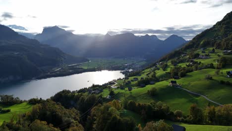 Aerial-approaching-shot-of-beautiful-swiss-mountains-with-village-and-lake-in-Amden-during-golden-sunset