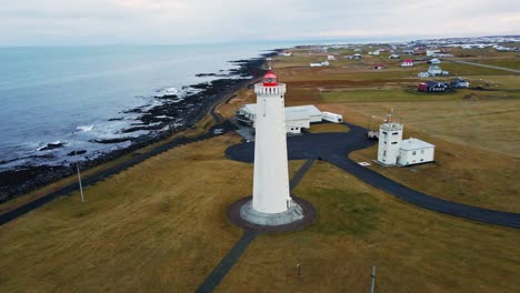 Aerial-of-a-tall-lighthouse,-the-drone-slowly-reveals-a-peaceful-sea-early-in-the-morning