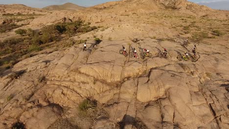 Disparo-De-Un-Dron-Siguiendo-A-Ciclistas-En-Una-Carrera-De-Bicicletas-En-Las-Montañas-Del-Desierto