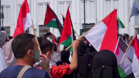 Partidario-Indonesio-Ondeando-Banderas-Indonesias-Y-Palestinas-En-La-Ciudad-Durante-La-Manifestación,-De-Cerca