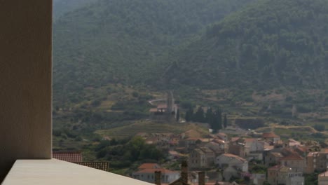 Hand-lifting-wine-glass-with-Mediterranean-mountain-town-view-background