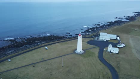 Drohne-Fliegt-über-Einen-Hohen-Leuchtturm-In-Richtung-Eines-Wunderschönen-Ozeans-In-Island