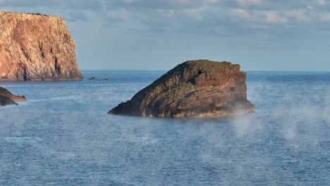 Rock-formations-surrounded-by-light-fog-at-sea-near-La-Vall-Beach
