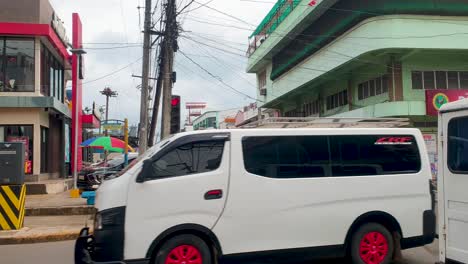 Street-view-of-Puerto-Princesa-lined-with-retail-shops,-cafes,-restaurants-and-businesses-with-inner-city-traffic-in-Palawan,-Philippines,-Southeast-Asia