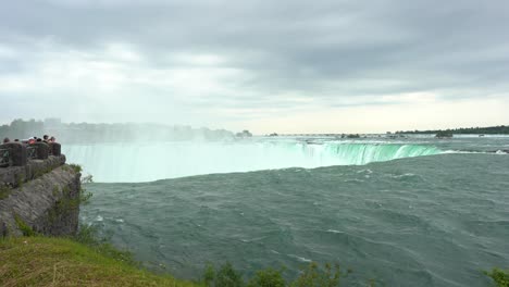 Niagara-Falls-landscape-view-over-water-flowing-down-the-waterfall-creating-steam,-on-a-cloudy-day