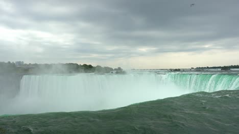 Niagara-Falls-landscape-view-of-water-flowing-down-the-waterfall-creating-steam,-on-a-cloudy-day