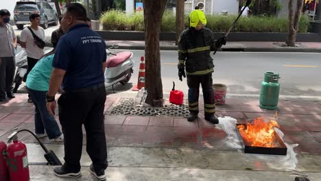 Feuerwehrmann-Führt-Demonstration-Des-Brandschutzes-Am-Arbeitsplatz-Durch-Und-Löscht-Feuer-Auf-Der-Straße-In-Saladaeng,-Bangkok,-Thailand